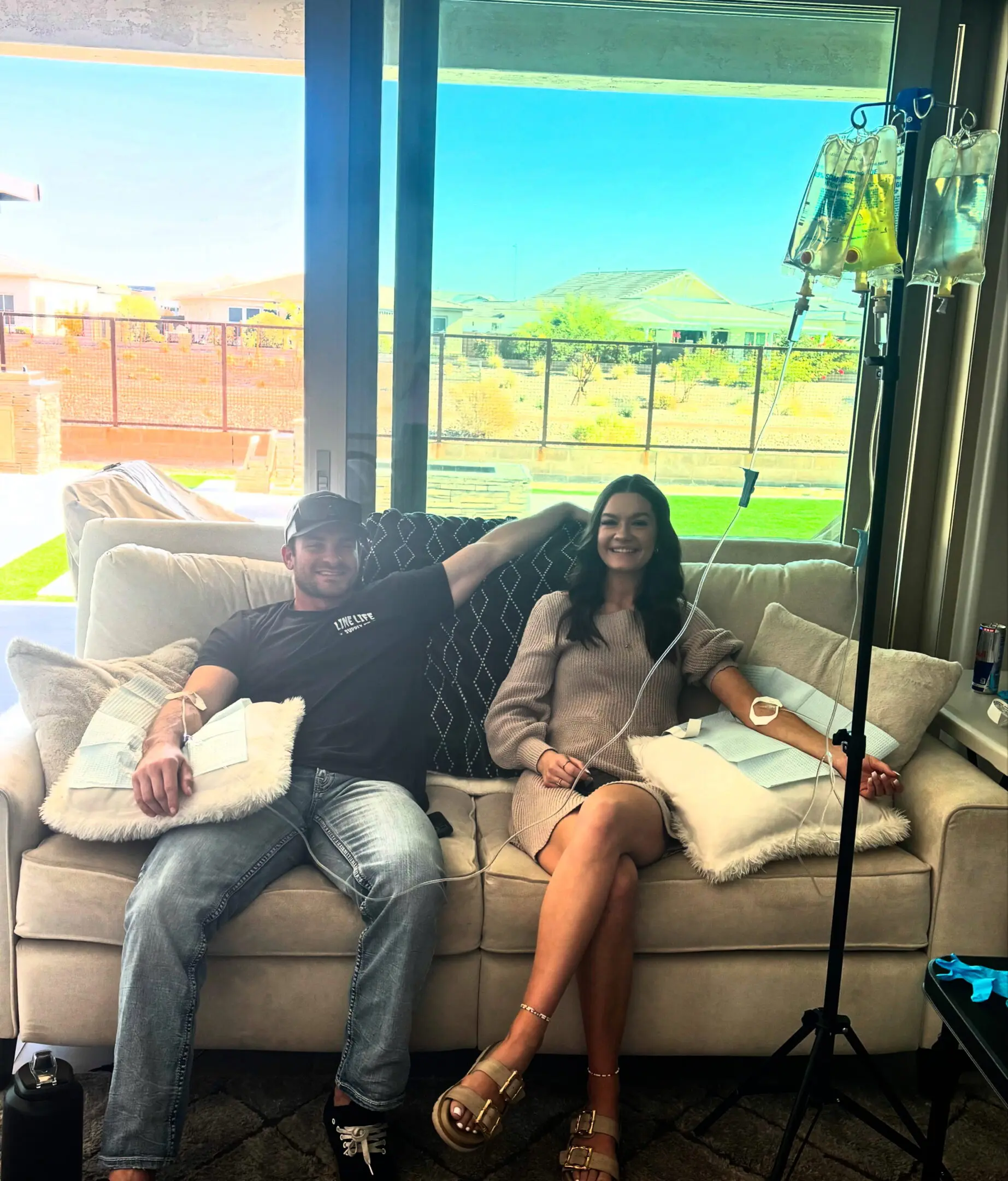 A couple relaxing on a couch in a sunlit living room with a dog.