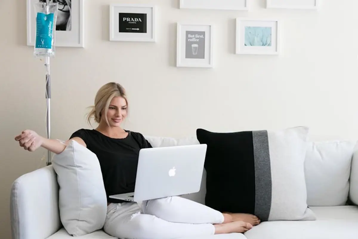 A woman sitting comfortably on a couch using a laptop.