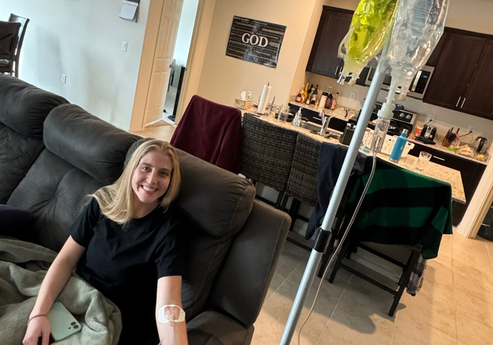 Woman sitting on floor receiving IV treatment at home.